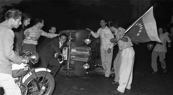 Venezuelanos nas ruas comemoram queda do ditador Jiménez Pérez ao lado de carro tombado. (Foto: Reprodução)