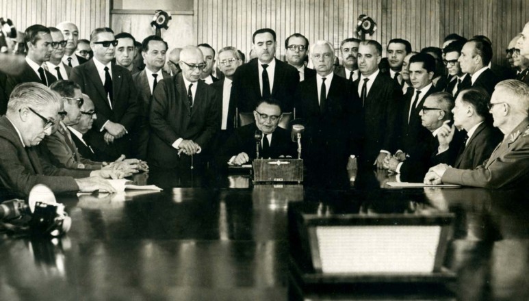  <strong> Castelo Branco,</strong> ao centro, assina o Ato Institucional nº 2, em Brasília. Aparecem na foto os dois futuros generais presidentes Costa e Silva (2º sentado à esq.) e Ernesto Geisel (sentado à dir., em primeiro plano)