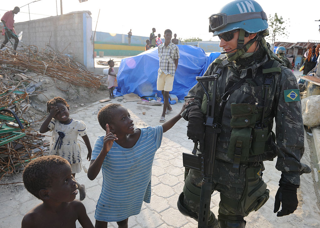 Militar brasileiro caminha com crianças haitianas durante patrulha na Cite Soleil. (Foto: Wikimedia Commons)