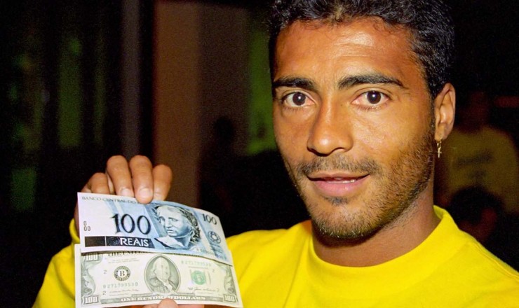  <strong> O jogador Romário compara </strong> as cédulas de R$ 100 e US$ 100; no lançamento da nova moeda, a seleção brasileira de futebol disputava a Copa do Mundo nos Estados Unidos   
