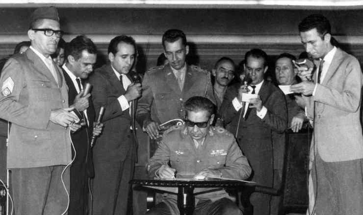  <strong> Arthur da Costa e Silva, </strong> representante do Exército no Comando Supremo da Revolução, assina o Ato Institucional da ditadura, primeiro de uma série de decretos autoritários